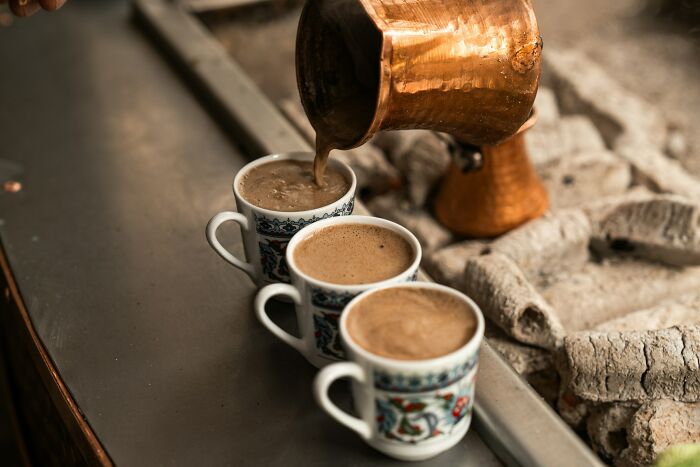 Traditional Greek coffee being poured into decorated cups in a rustic village setting, reflecting Greek village life. Traditional Greek coffee being poured into decorated cups in a rustic village setting, reflecting Greek village life.