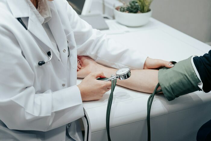 Doctor in a white coat measuring patient's blood pressure, highlighting everyday things more dangerous for your health than you realize.