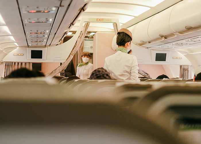 Flight attendants inside an airplane cabin managing parents and kids while addressing noise during the flight.