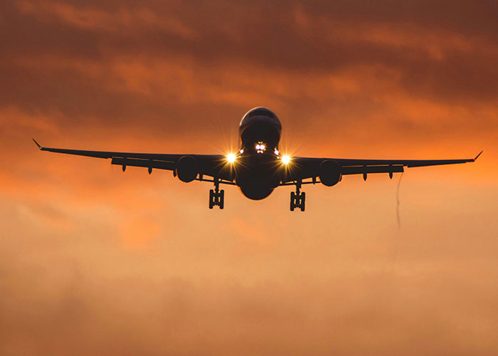 Airplane approaching at sunset with bright lights, illustrating the noise challenges for parents and kids during flights.