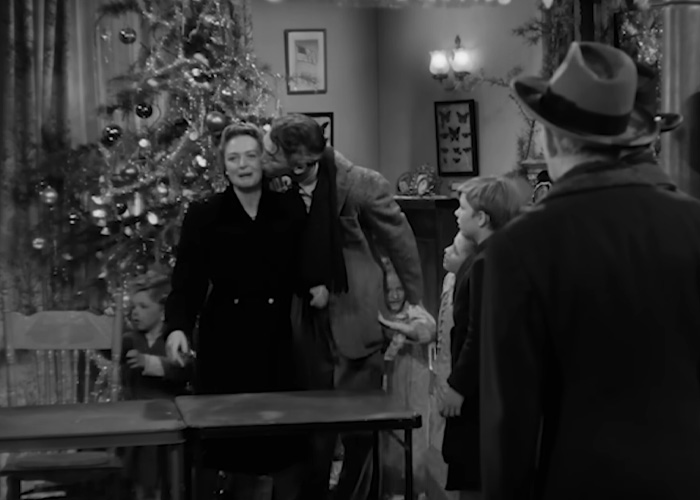 Family gathered around Christmas tree in a classic black and white holiday film scene from a beloved Christmas classic.