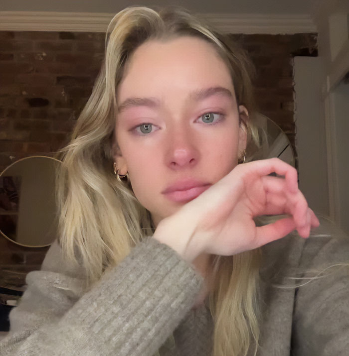 Young woman with blonde hair and a gray sweater wiping tears, related to friend of NYU shove victim viral video exposure. Young woman with blonde hair and a gray sweater wiping tears, related to friend of NYU shove victim viral video exposure.