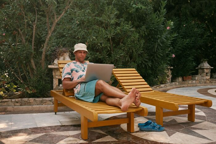 Man working on laptop while lounging outdoors, representing the digital nomad lifestyle beyond Instagram highlights.