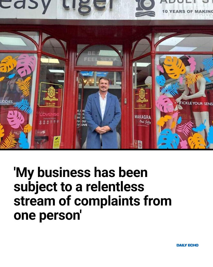 Man standing outside a shop with colorful window decorations, illustrating local newspaper headlines going mad.