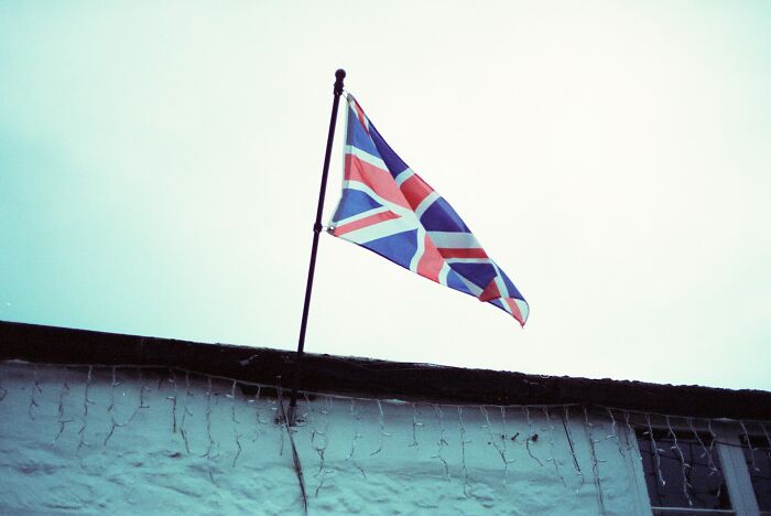 Union Jack flag flying above a house roof as people share historical facts unknown until recently.