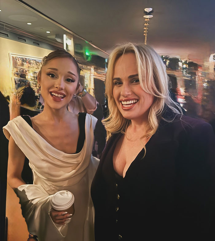 Rebel Wilson and Ariana Grande smiling together at an event with a bizarre detail noticed in the background. Rebel Wilson and Ariana Grande smiling together at an event with a bizarre detail noticed in the background.