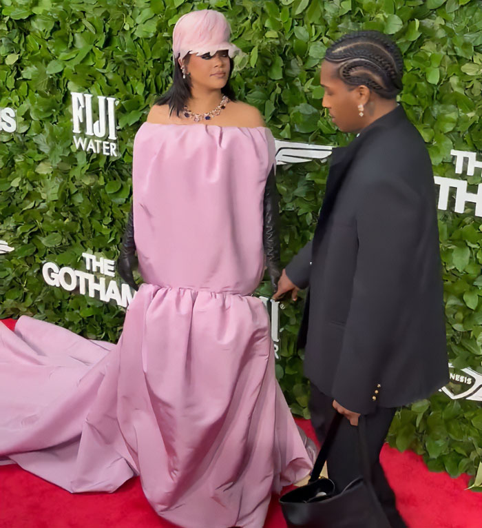 Rihanna on the red carpet wearing a voluminous pink gown with black gloves, sparking wild reactions about the diaper bag.