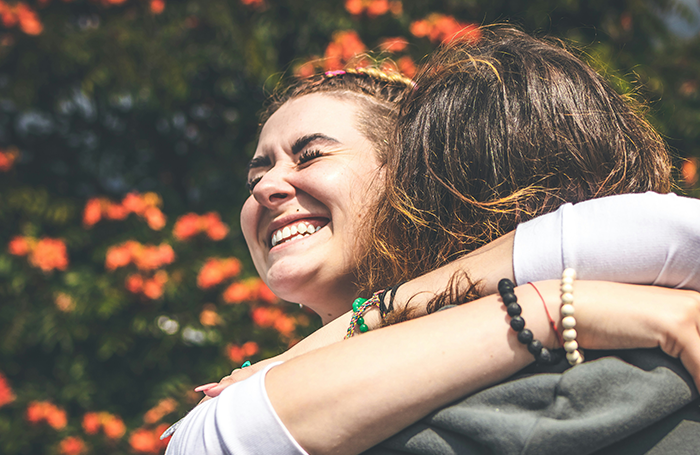 Two women hugging outdoors, smiling and showing support in a warm moment related to aunt pay niece tummy tuck drama.