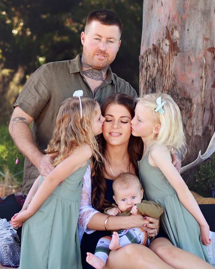 Family portrait showing a mom with children and husband, related to mom on life support after traveling to Vietnam for plastic surgery