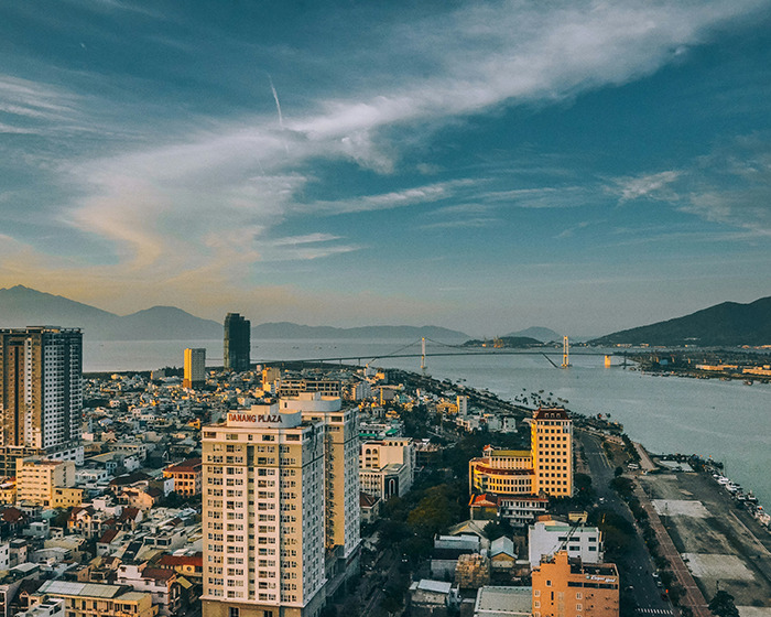 Cityscape of Da Nang, Vietnam, with buildings and the river under a cloudy sky, related to plastic surgery travel risks.