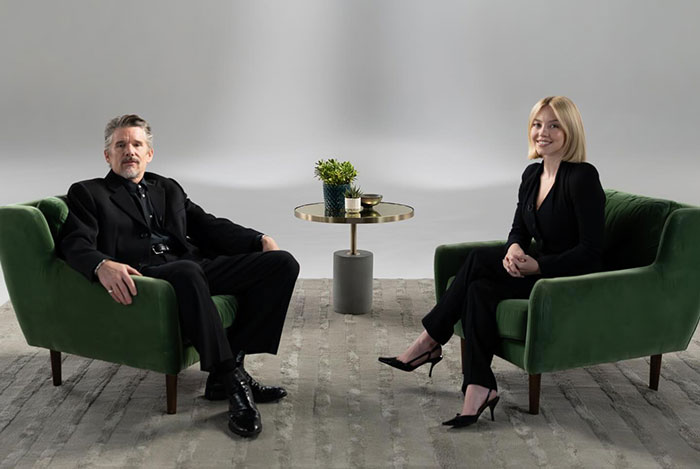 Ethan Hawke and Sydney Sweeney seated on green chairs in a minimalist studio setting, sparking online firestorm discussions. Ethan Hawke and Sydney Sweeney seated on green chairs in a minimalist studio setting, sparking online firestorm discussions.
