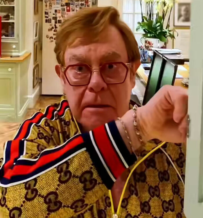 Elton John wearing glasses and a patterned jacket in his kitchen responding to fans trolling a random kitchen detail. Elton John wearing glasses and a patterned jacket in his kitchen responding to fans trolling a random kitchen detail.