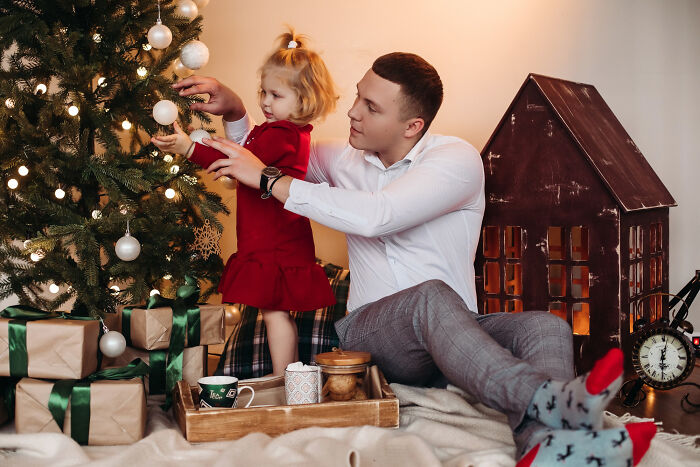 Man and child decorating Christmas tree while wife and baby are left alone, highlighting husband ditching family on Christmas. Man and child decorating Christmas tree while wife and baby are left alone, highlighting husband ditching family on Christmas.