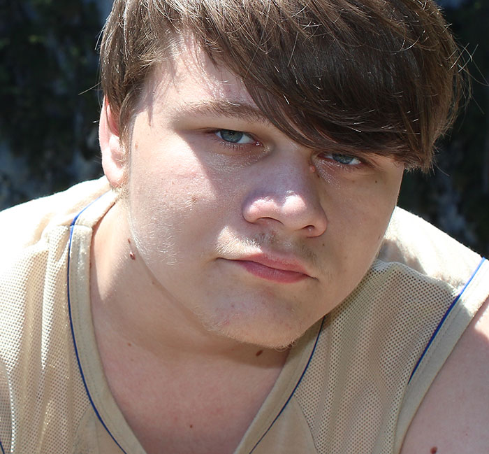 Close-up of a young man with light brown hair outdoors, representing chaotic good actions shared by 50 people.