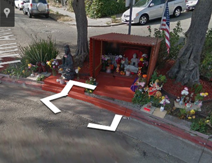 Street shrine with statues and flowers by the sidewalk, an example of a chaotic good community tribute.