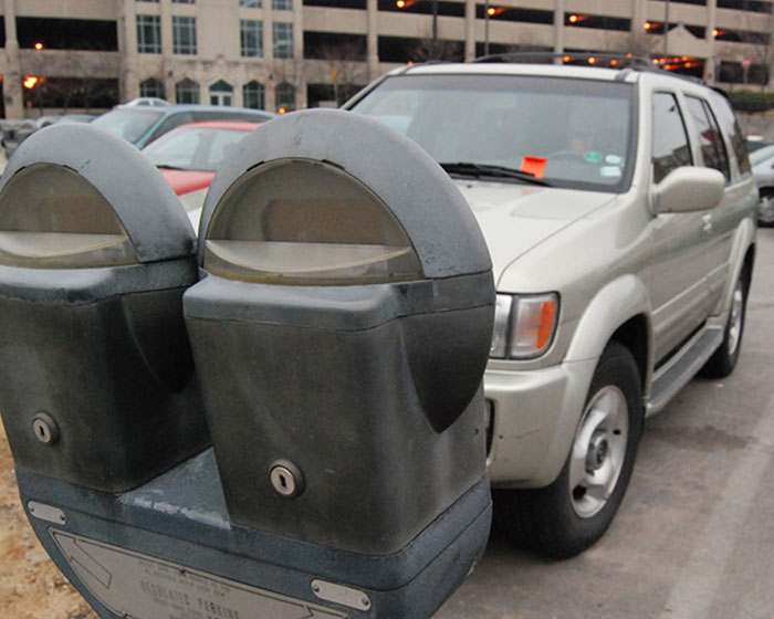 Parking meter and silver SUV in an urban setting, capturing a chaotic good scene in everyday city life.