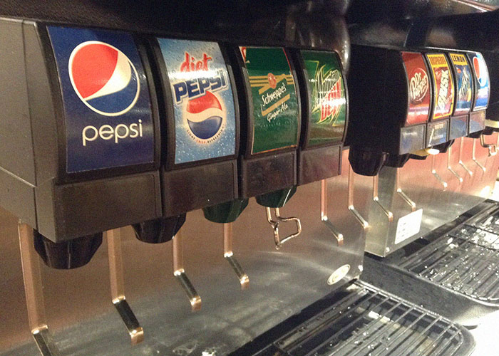 Soda fountain machine with various popular soft drink options revealing industry secrets to customers.