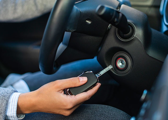 Person inserting car key into ignition, illustrating industry secrets revealed to customers in various jobs.
