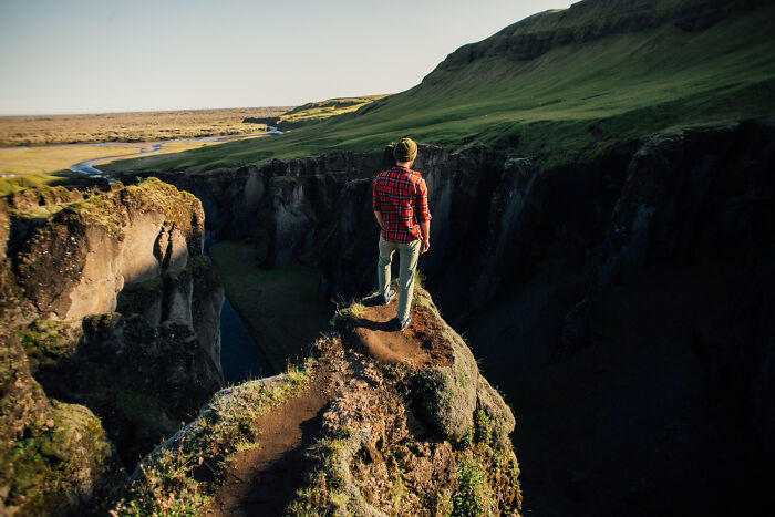 Person standing at edge of cliff overlooking canyon, symbolizing the biggest bullet dodged without realizing it.