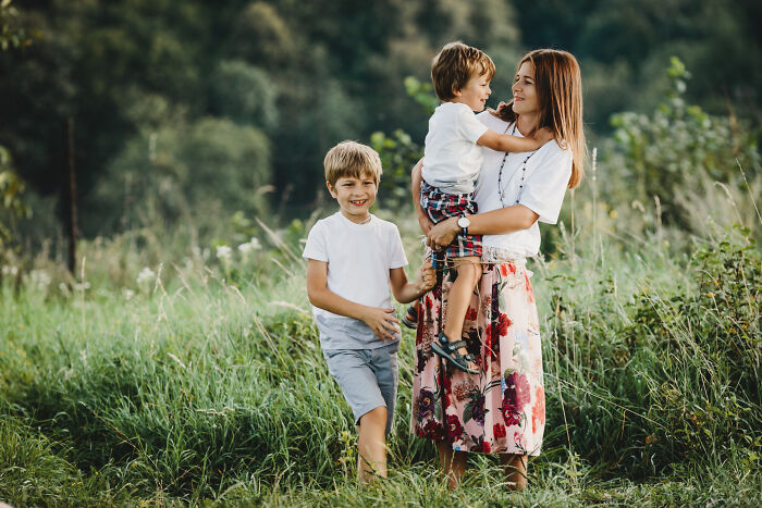 Woman with two children outdoors in a green field, portraying a moment of dodging a big bullet without realizing it.