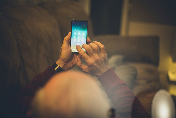Elderly person holding smartphone, entering passcode, illustrating secrets people refuse to reveal to their parents.