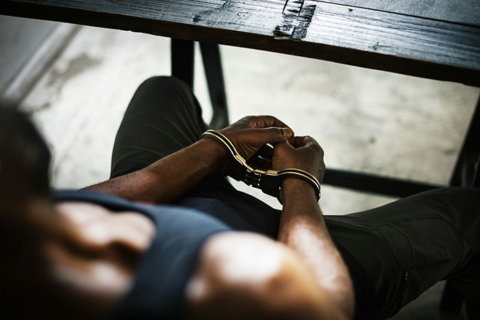 Person sitting with hands cuffed, symbolizing deep secrets people refuse to reveal to their parents to avoid devastation.