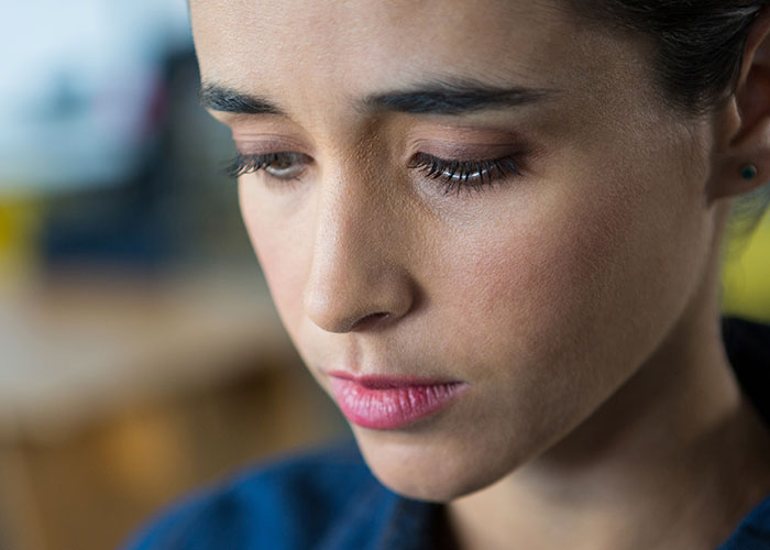 Close-up of a woman looking down thoughtfully, reflecting on engagement and fiancé’s lie about her family.