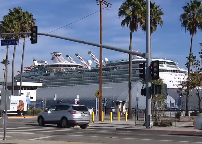 Large cruise ship docked at harbor with palm trees and moving cars at intersection under traffic lights. Large cruise ship docked at harbor with palm trees and moving cars at intersection under traffic lights.
