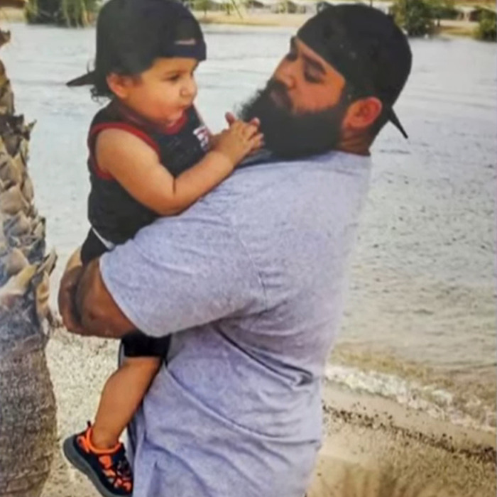 Man with a beard holding a child by the water, illustrating cruise passenger's body stuffed in fridge incident. Man with a beard holding a child by the water, illustrating cruise passenger's body stuffed in fridge incident.