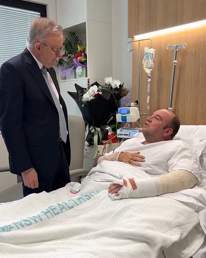Hospital visit of Bondi Beach hero with cast, speaking to a man in a suit in a hospital room setting. Hospital visit of Bondi Beach hero with cast, speaking to a man in a suit in a hospital room setting.