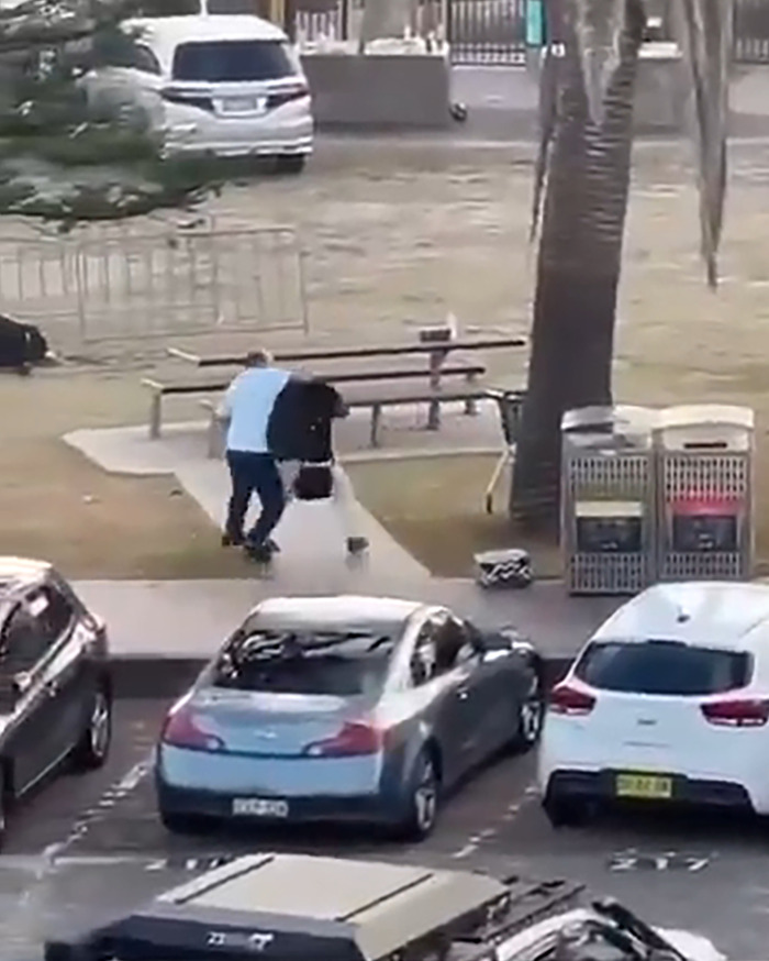Man confronting attacker near skate park at Bondi Beach, with parked cars and picnic bench in background. Man confronting attacker near skate park at Bondi Beach, with parked cars and picnic bench in background.