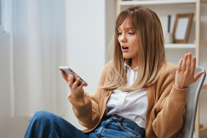 Young woman reacting with surprise while looking at phone, possibly frustrated with boyfriend editing face every photo. Young woman reacting with surprise while looking at phone, possibly frustrated with boyfriend editing face every photo.