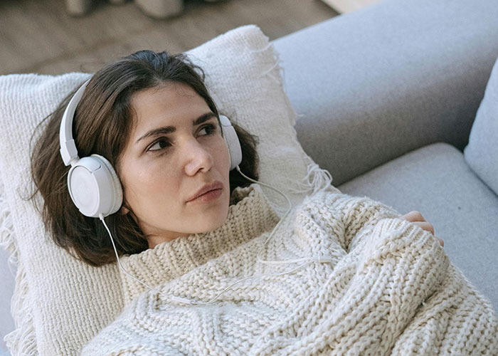 Young man in cozy sweater listening with headphones, reflecting on losing girlfriend over a girl at work crush.