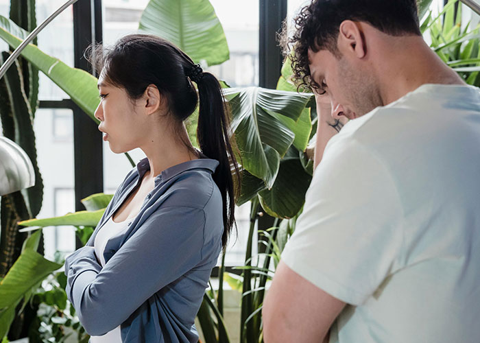 Man looking upset while woman with crossed arms turns away, reflecting a relationship struggle over a work crush.