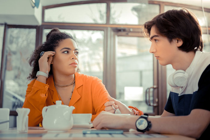 Get Him To A Doctor: concerned woman confronting boyfriend at cafe, he looks distant, teapot and cups on table