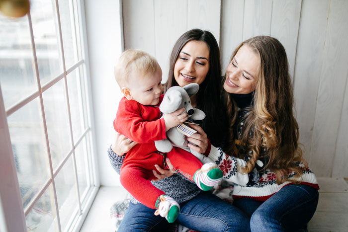 Two women and a baby by a window, illustrating family drama and custody court involving brother who abandoned his kid. Two women and a baby by a window, illustrating family drama and custody court involving brother who abandoned his kid.