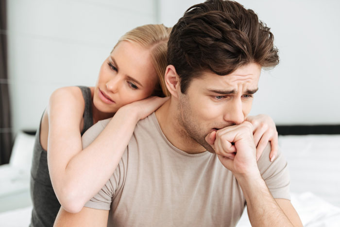 Concerned woman comforting a worried man on bed, conveying brother money wife family stress.