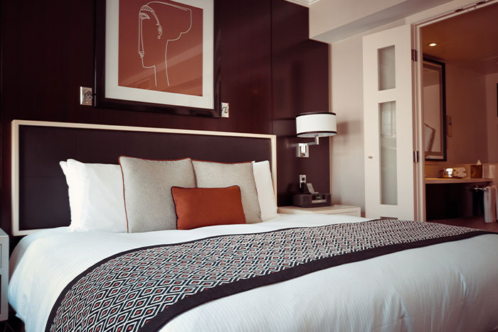 Modern bedroom with a neatly made bed, pillows, and a nightstand, symbolizing woman welcomes brother’s family stay.