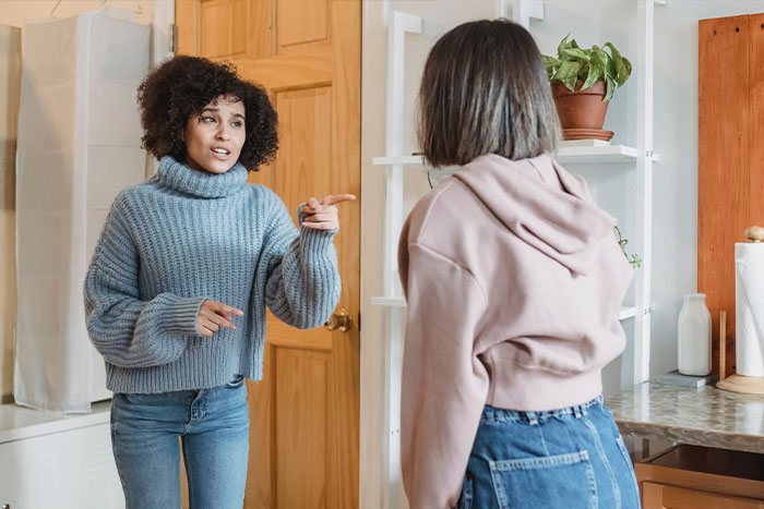 Two women in a kitchen having a tense conversation, depicting a woman welcoming her brother’s family and complaints. Two women in a kitchen having a tense conversation, depicting a woman welcoming her brother’s family and complaints.
