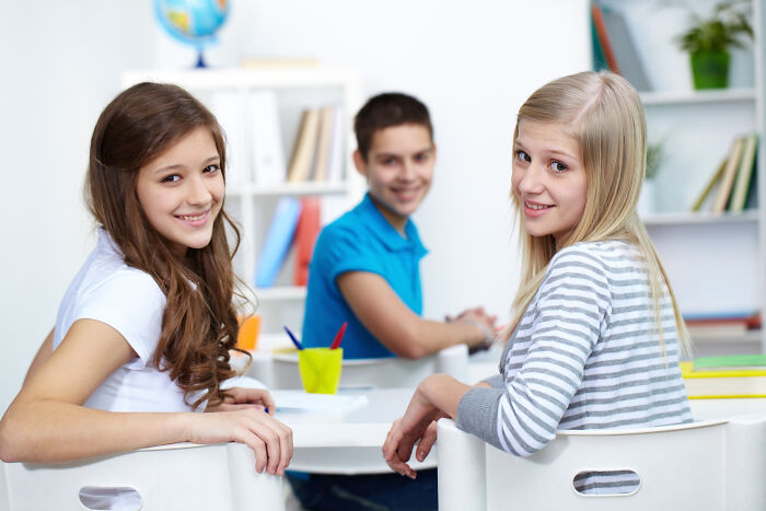 Three smiling students sitting at a table, illustrating small decisions leading to unexpected life-altering consequences.