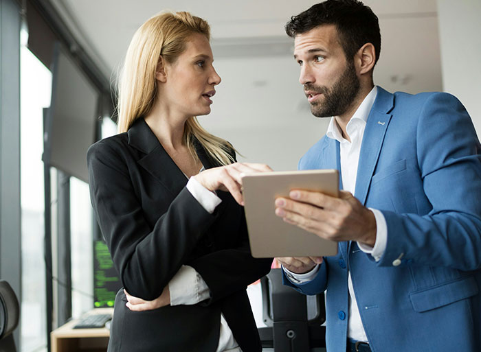 Woman looking weirded out as coworker in blue suit insists on calling her his work mom in office setting