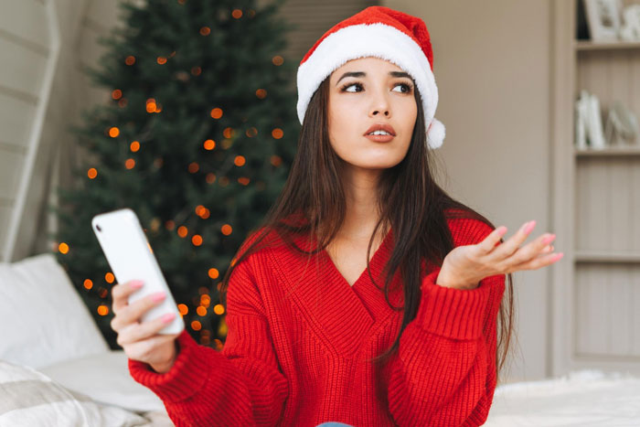 Young woman in a Santa hat and red sweater looking frustrated during Christmas dinner planning with lazy relatives and pizza options. Young woman in a Santa hat and red sweater looking frustrated during Christmas dinner planning with lazy relatives and pizza options.