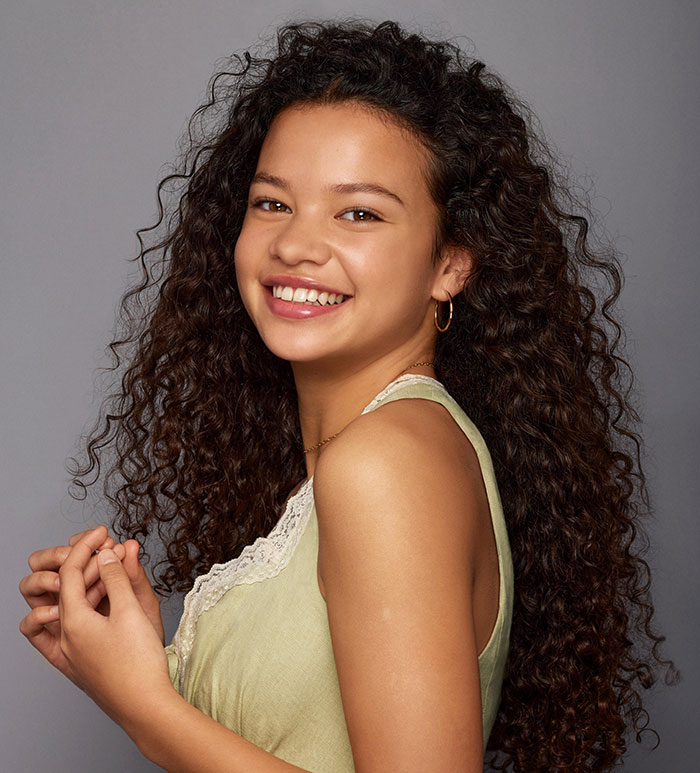 Young woman with curly hair smiling against a gray background, representing perspectives on what happened to Disney. Young woman with curly hair smiling against a gray background, representing perspectives on what happened to Disney.