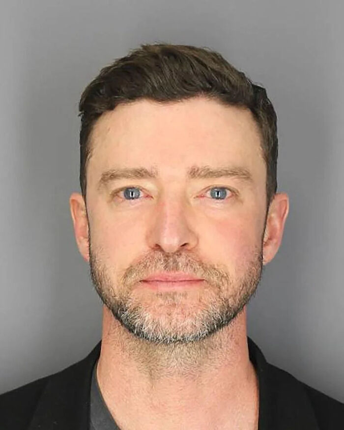 Close-up mugshot of a man with blue eyes and beard, featured among infamous celebrity mugshots and arrest reasons.