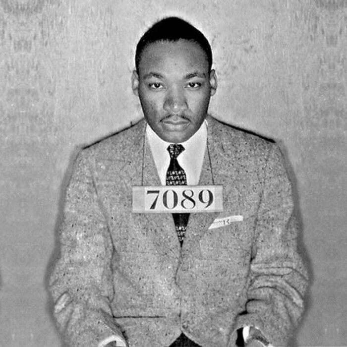 Black and white mugshot of a man wearing a suit with a number plate, part of infamous celebrity mugshots collection.