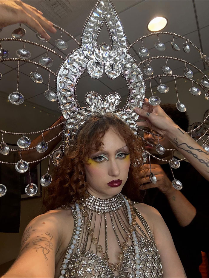 Chappell Roan wearing elaborate jeweled costume and headpiece, preparing backstage amid final touches.