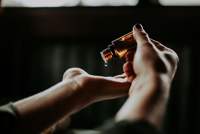 Person pouring essential oil from a small bottle onto their hand, illustrating unexpected moments at funerals.