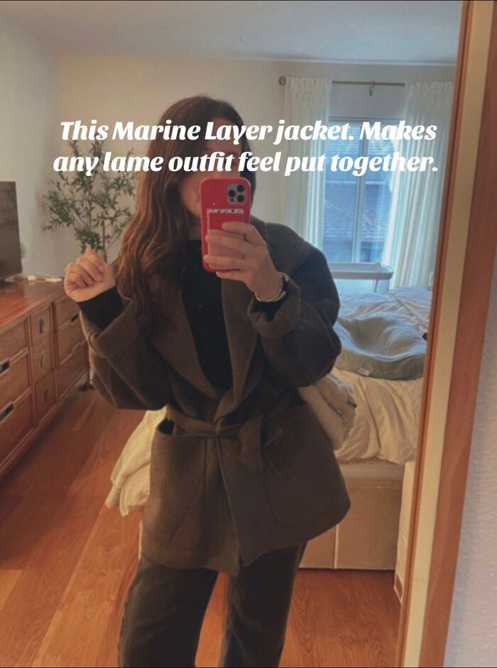 Woman wearing a Marine Layer jacket, taking a mirror selfie showcasing one of the most recommended Christmas gifts.