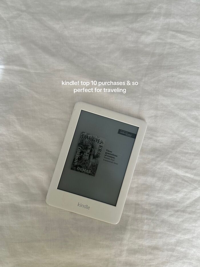White Kindle e-reader displaying a book cover on a soft fabric surface, ideal for Christmas gifts recommendations.