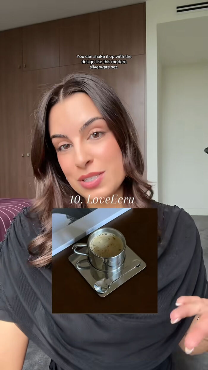 Woman presenting a modern silverware set as a popular Christmas gift in a home setting with a wooden cabinet background.